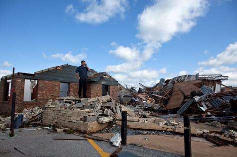 In the aftermath of a severe tornado, owner Frank Evans stands on the rubble that was the Quik Pawn Shop