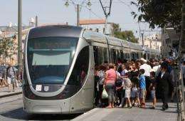 Israelis gather to board a train on the Jerusalem light rail system's first day of operation today