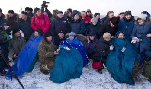 (L-R) Mike Fossum, Sergei Volkov and Satoshi Furukawa sit swathed in blue rugs and blankets moments after they land