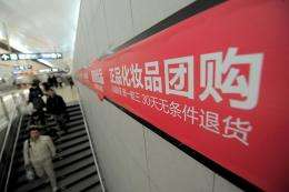 People walking pass signboards for a Chinese Internet group buying company at a subway station in Beijing