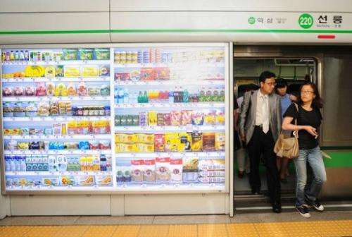 South Koreans get off a subway car next to a virtail retail shop (L) wall at Seolleung subway station in Seoul