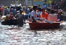 Thai people commute through floodwaters in Bangkok on Friday