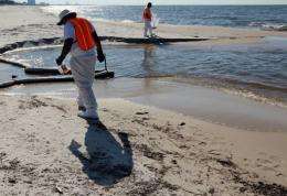 Workers look to clear off some of the oil residue on the beach from the Gulf of Mexico oil spill