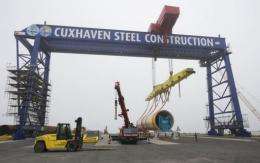 Workers prepare a wind turbine steel tower at the offshore terminal of the Offshore Base Cuxhaven