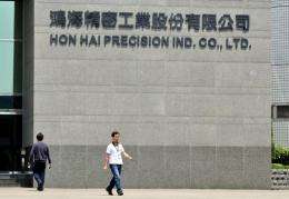 Workers walk in front of Taiwanese electronics giant Hon Hai's headquarters in Tuchung city