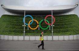 A man walks past Olympic rings outside the Aquatic Centre at the London 2012 Olympic Park in east London