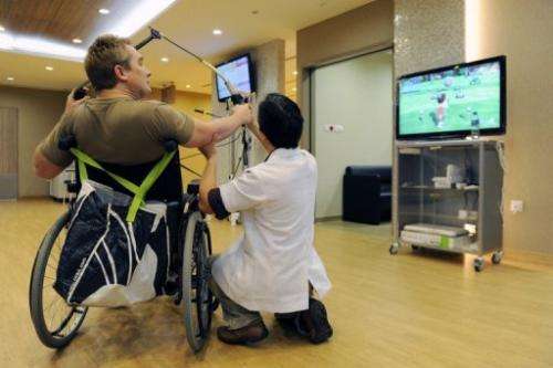 A patient recovering from stroke takes aim at a target with the help of senior occupational therapist Donald Xu Dong