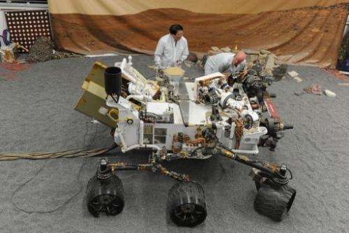 Jet Propulsion Laboratory (JPL) engineers examine a full size engineered model of the Mars rover Curiosity