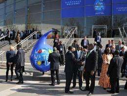 Participants talk next to logo of the 6th World Water Forum in Marseille