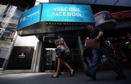 People walk past a sign welcoming Facebook at the NASDAQ stock exchange