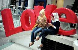 Two women enjoy social networking by using their mobile phone devices in Jakarta