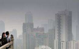 A couple look across the Hong Kong skyline shrouded by smog