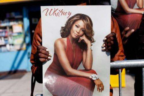 A fan holds a poster of Whitney Houston at the singer's February 18, 2012 funeral in Newark, New Jersey