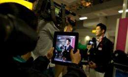 A journalist uses a tablet computer as a member of South Korea's gymnastics team is interviewed upon arrival at Heathrow