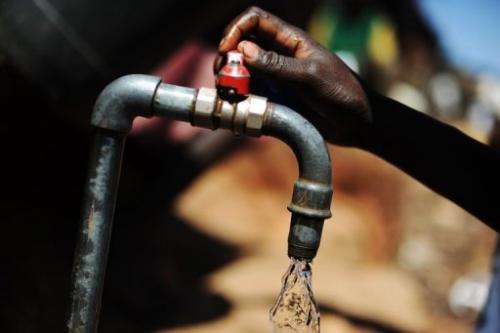 A Kenyan woman turns on a tap at a water distribution site in the Kibera slum of Nairobi