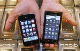 A manager holds an Apple iPhone (L) and Motorola's Droid smartphone (R)