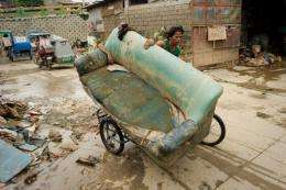 A man uses a bicycle to transport a sofa chair in Tomana slum