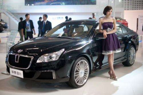 A model stands beside a 'B11' car by Chinese manufacturer Hawtai Motors, at the Auto China show in Beijing