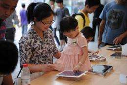 A mother and daughter play with an Apple iPad at an Apple store in Shanghai