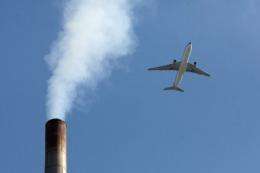 An aircraft flies past a smoke-stack in Beijing