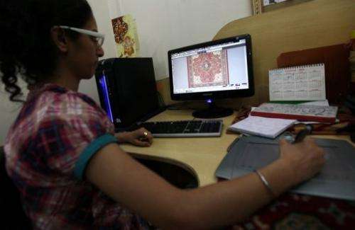 An Indian designer uses a computer to put the finishing touches to a carpet design