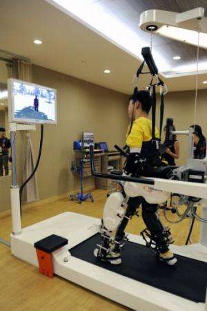 A patient who has cerebral palsy looks at his virtual avatar as he exercises on the Lokomat robotic gait trainer