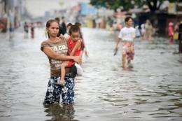 A woman holding a young boy wades through floodwaters in a street in the township of Apalit on the outskirts of Manila