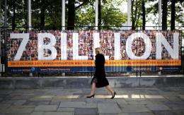 A woman walks past a UN sign announcing symbolically that the world population hit 7 billion in 2011