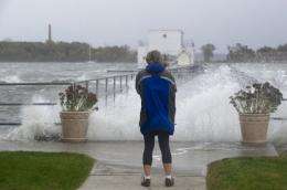 A woman watches waves crash onto a pier on City Island in New York