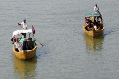 Cambodian and foreign tourists on boats to spot dolphins along the Mekong river on December 6, 2012