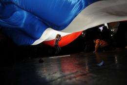 Children play under a giant French flag during a campaign meeting in Paris