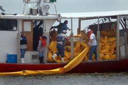 Fishermen use their shrimp boat to place oil booms into the water in May 2010 near Shell Beach, Louisiana