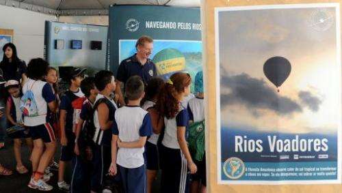 Gerard Moss (C) talks to children during an exhibition of his "Rios Voadores" (Flying Rivers) project