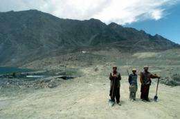 Pakistani labourers stand with mountains of the Himalayan Karakoram range