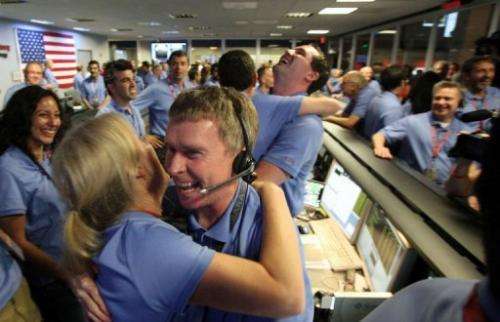 Telecom engineer Peter Ilott (C) hugs a colleague, celebrating a successful landing for NASA's Curiosity rover