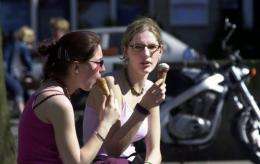 Two young women enjoy ice cream on a sunny day in Brussels