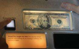 Visitors try to pick counterfeit bills from the real ones displayed at a museum in the Federal Reserve Bank of Chicago
