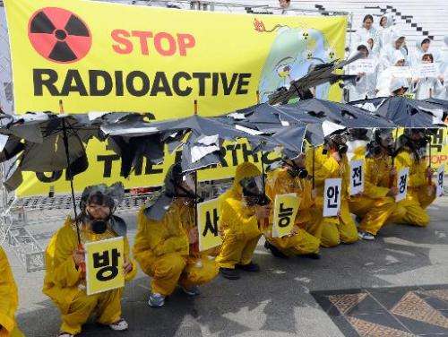 Activists wear yellow raincoats and gas masks and hold torn umbrellas during a rally in Seoul on April 21, 2011 to oppose nuclea
