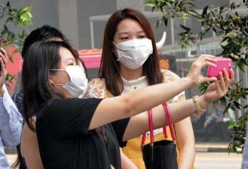 A group of office workers wearing face masks take a picture in Singapore on June 20, 2013