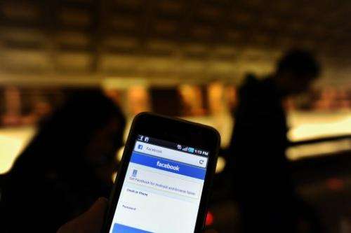 A man checks his Facebook page on his smartphone in a metro station in Washington, DC on May 9, 2012