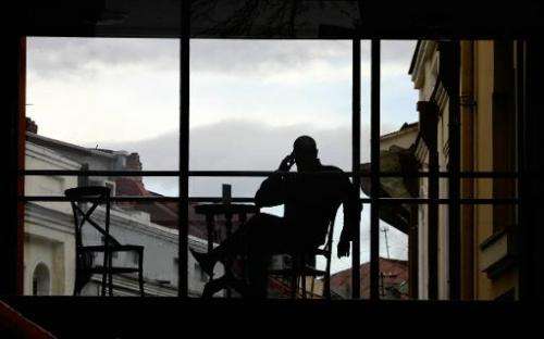A man talks on his mobile phone as he enjoys the sunset from a roof bar in Tbilisi, March 29, 2005