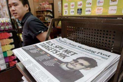 A man walks past a paper carrying the story of former US spy Edward Snowden (R), Hong Kong, June 13, 2013