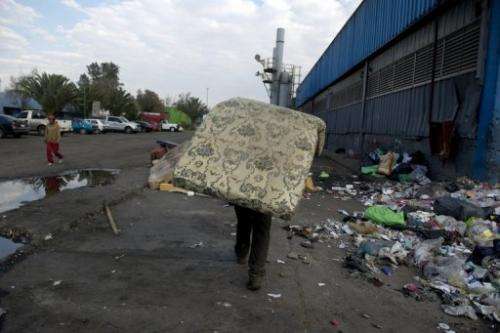 A scavenger carries a mattress at the &quot;Bordo Poniente&quot; garbage dump in Mexico City on January 18, 2012