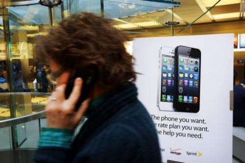 A woman walks past an Appple iPhone 5 advertisement in New York City on January 14, 2013