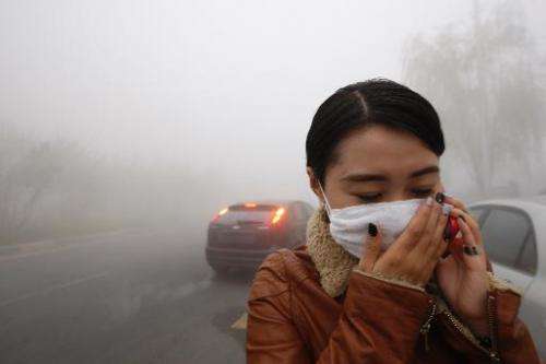 A woman wearing a mask covers her mouth with her hands as she walks in the smog in Harbin, China's Heilongjiang province, on Oct