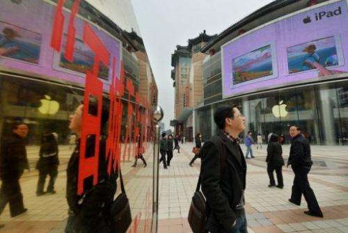 Chinese tourists walk past an Apple store in Beijing on March 29, 2013