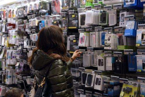 Customers look at mobile phone accessories at a shop on November 27, 2012 in Paris