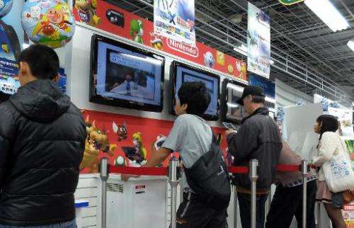 Customers play Nintendo's portable videogame console at a Tokyo electronics shop on October 30, 2013
