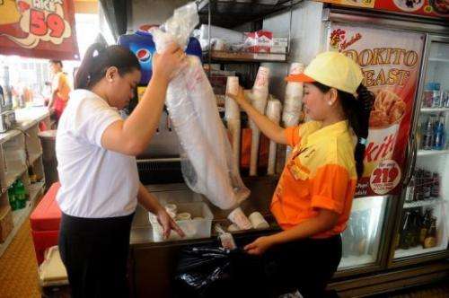 Employees of a fast food store put plastic cups into a trash bag, in Makati City, on June 20, 2013