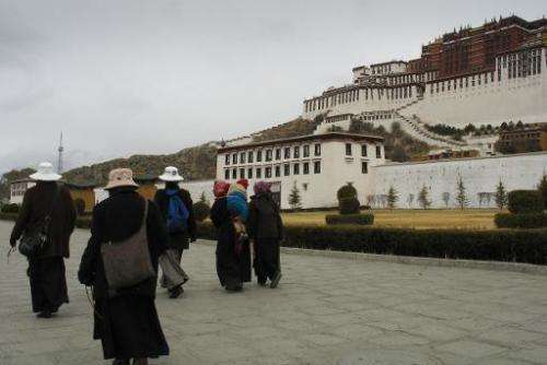 File photo of Tibetans passing the Potala Palace in the capital Lhasa, where pollution levels have reached new heights, shroudin